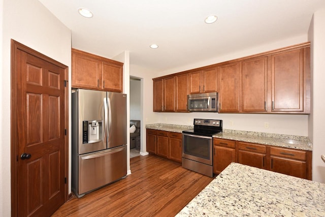 kitchen featuring brown cabinets, dark wood-type flooring, light stone counters, recessed lighting, and stainless steel appliances