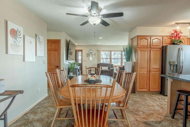 dining space featuring a ceiling fan, baseboards, and a textured ceiling