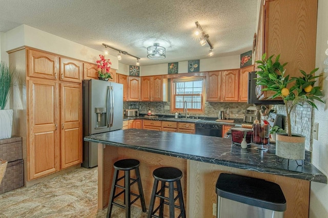 kitchen featuring tasteful backsplash, stainless steel fridge with ice dispenser, dishwasher, a peninsula, and a sink