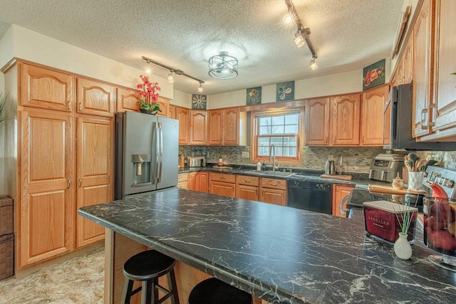 kitchen with a breakfast bar, a peninsula, a sink, decorative backsplash, and appliances with stainless steel finishes