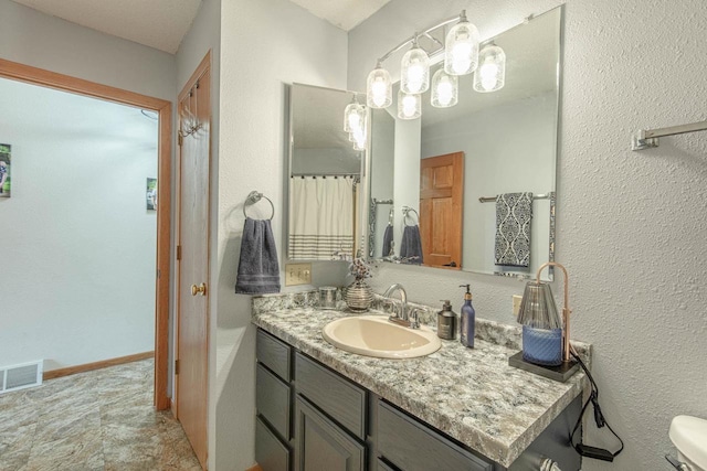 bathroom featuring visible vents, baseboards, toilet, and vanity