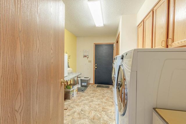 laundry room featuring cabinet space, a textured ceiling, and washer and clothes dryer