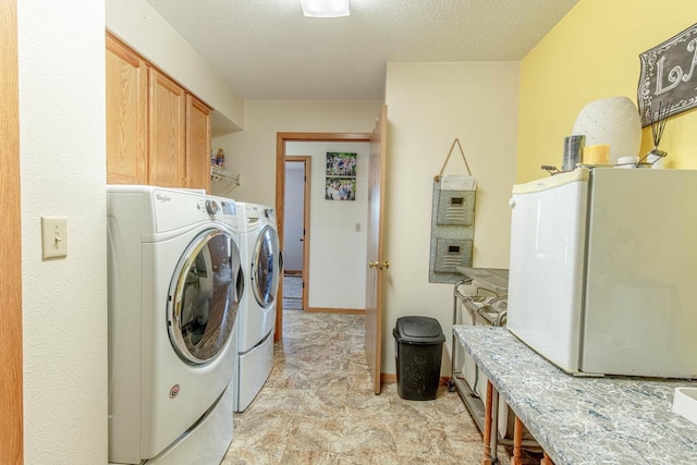 washroom featuring washing machine and dryer, cabinet space, baseboards, and a textured ceiling