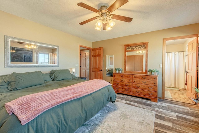 bedroom with a textured ceiling, a ceiling fan, and wood finished floors