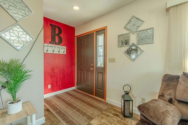 foyer with baseboards, a textured ceiling, and wood finished floors