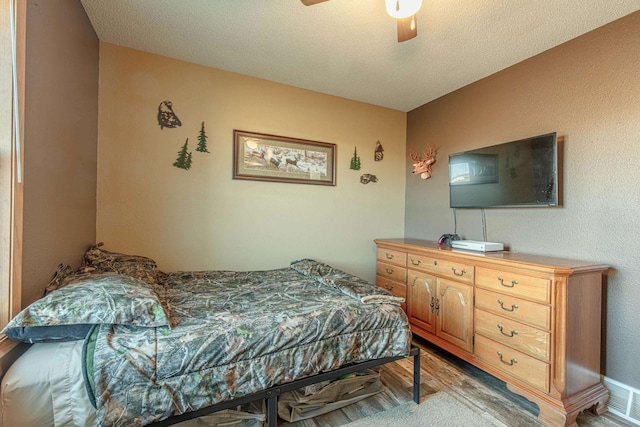 bedroom featuring light wood-type flooring, a textured ceiling, and a ceiling fan