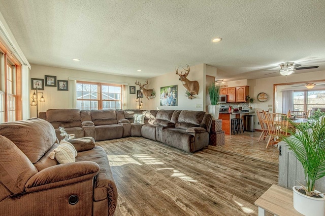 living room featuring recessed lighting, a textured ceiling, light wood-style flooring, and a ceiling fan