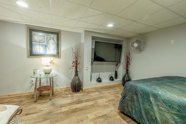 bedroom with a drop ceiling, baseboards, and wood finished floors