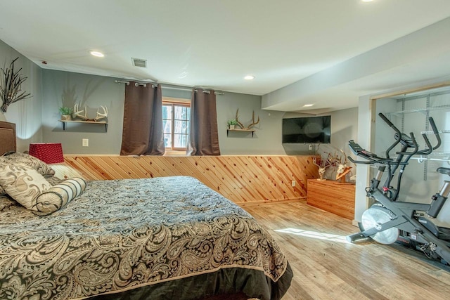 bedroom with visible vents, wood finished floors, recessed lighting, wood walls, and wainscoting