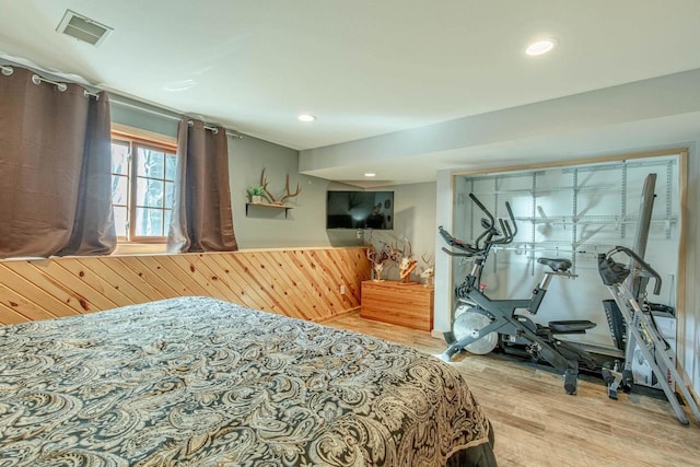 bedroom featuring wood finished floors, visible vents, recessed lighting, wood walls, and wainscoting