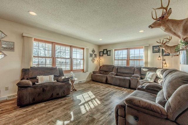 living area with visible vents, recessed lighting, a textured ceiling, and wood finished floors