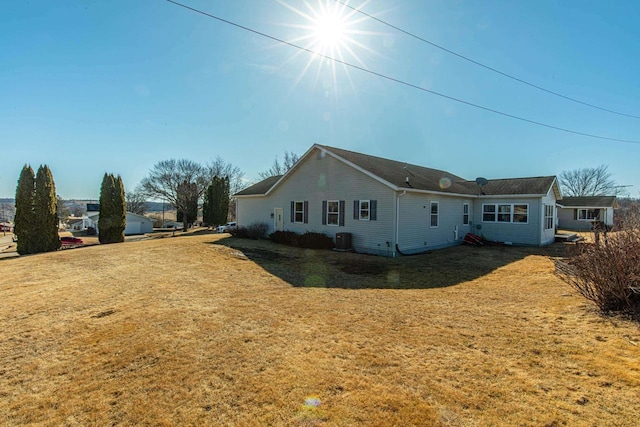 rear view of house featuring a lawn and central AC