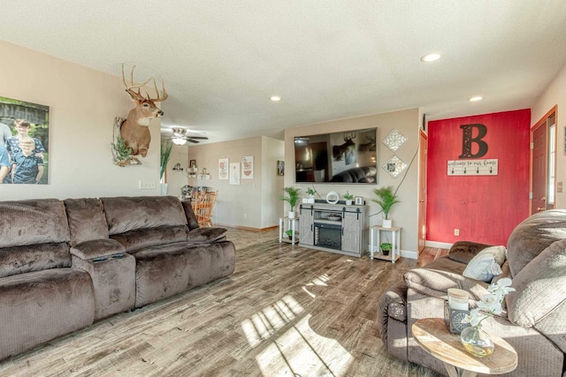 living area with baseboards, recessed lighting, a fireplace, wood finished floors, and a textured ceiling