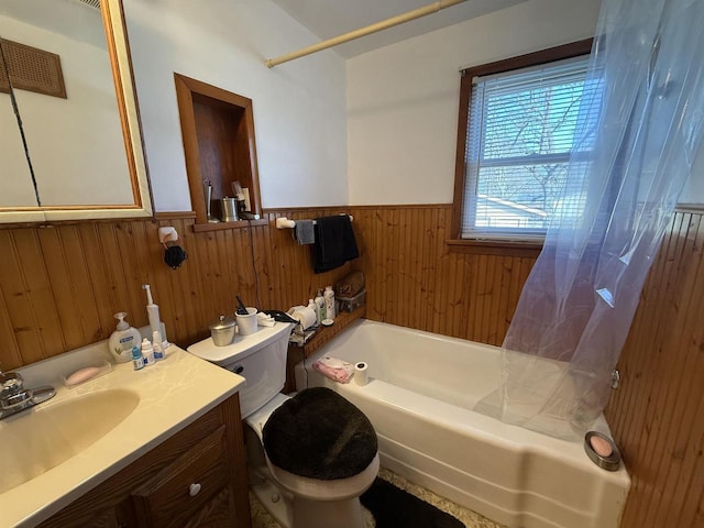 full bath with toilet, wooden walls, wainscoting, tub / shower combination, and vanity