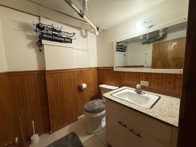 bathroom featuring toilet, wooden walls, wainscoting, tile patterned flooring, and vanity