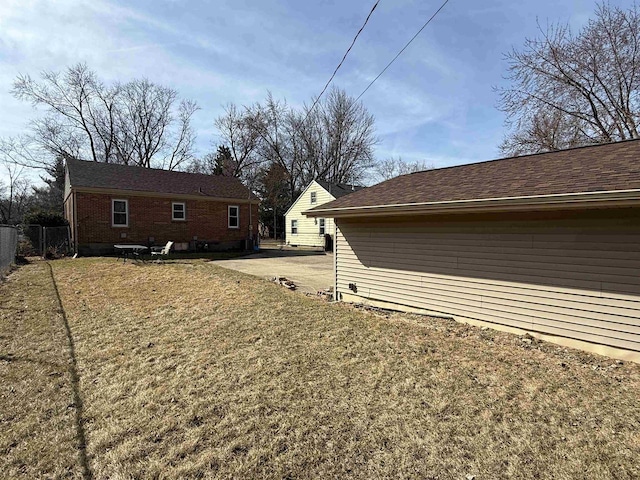 view of property exterior with a yard, a patio, brick siding, and fence