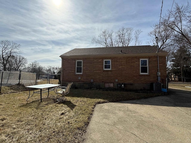 rear view of property with brick siding, roof with shingles, and fence