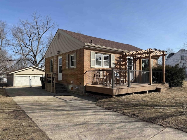 view of front facade with an outbuilding, fence, a pergola, a detached garage, and brick siding