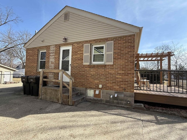 view of front of home with a wooden deck, brick siding, and a pergola