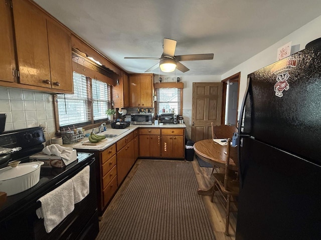 kitchen with light countertops, decorative backsplash, brown cabinets, black appliances, and a ceiling fan