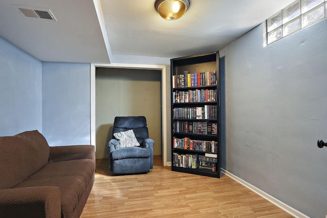 living area featuring light wood-type flooring, visible vents, and baseboards