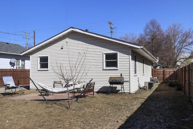 rear view of property with central AC unit and a fenced backyard