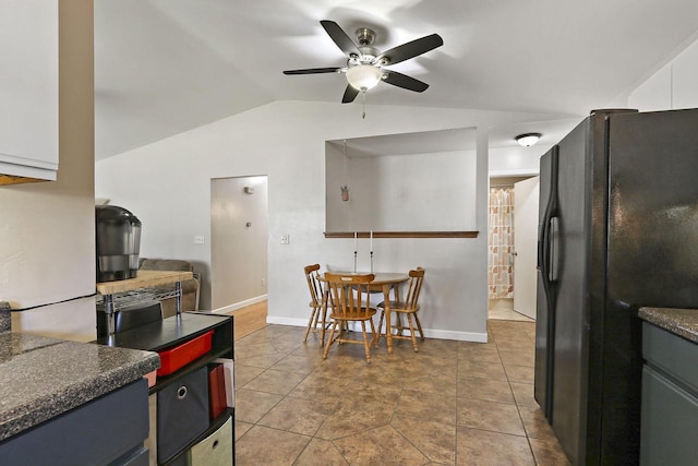 kitchen featuring dark countertops, baseboards, ceiling fan, vaulted ceiling, and black refrigerator with ice dispenser