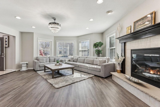 living room with a tiled fireplace, recessed lighting, wood finished floors, and baseboards