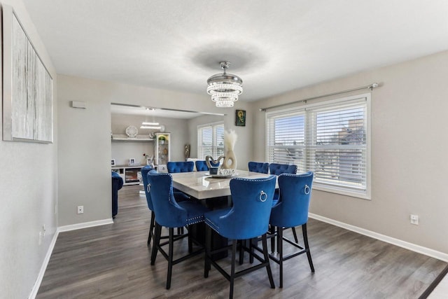 dining room with dark wood-style floors, a notable chandelier, and baseboards