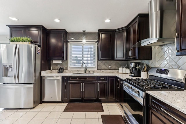 kitchen featuring light stone counters, light tile patterned flooring, a sink, appliances with stainless steel finishes, and wall chimney range hood