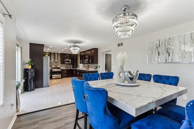 dining space with a chandelier, visible vents, and light wood finished floors