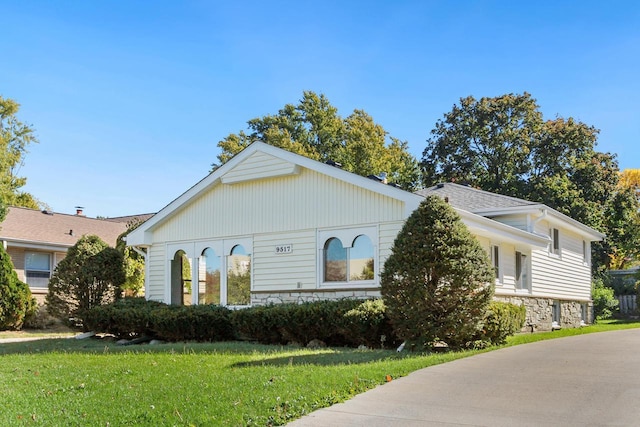 view of front of house with stone siding and a front lawn