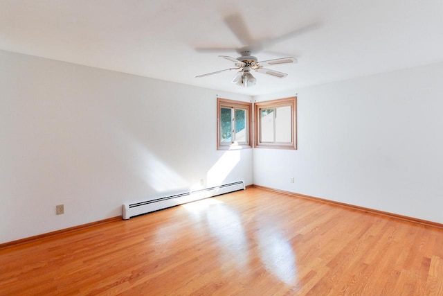 empty room featuring wood finished floors, baseboards, baseboard heating, and ceiling fan