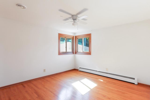 empty room featuring baseboard heating, light wood-style flooring, a ceiling fan, and baseboards