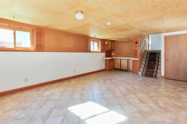 interior space featuring baseboards, wood ceiling, light tile patterned flooring, and stairs