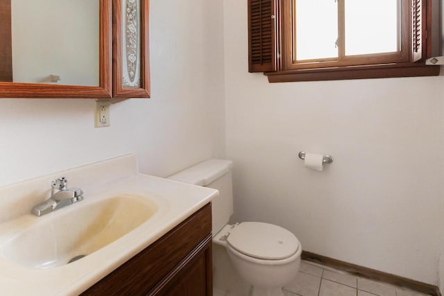 half bathroom featuring tile patterned floors, baseboards, toilet, and vanity