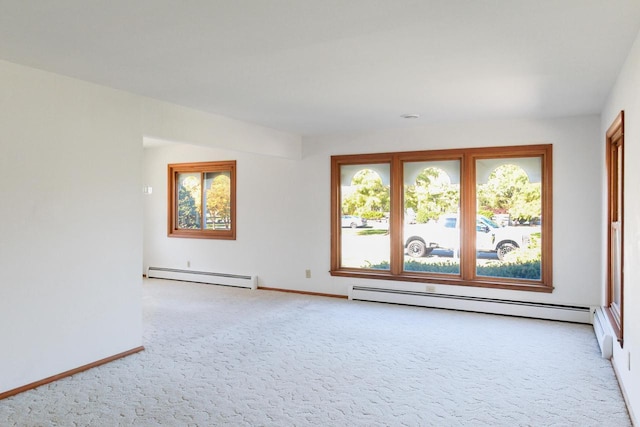 empty room featuring a baseboard heating unit, light colored carpet, and baseboards