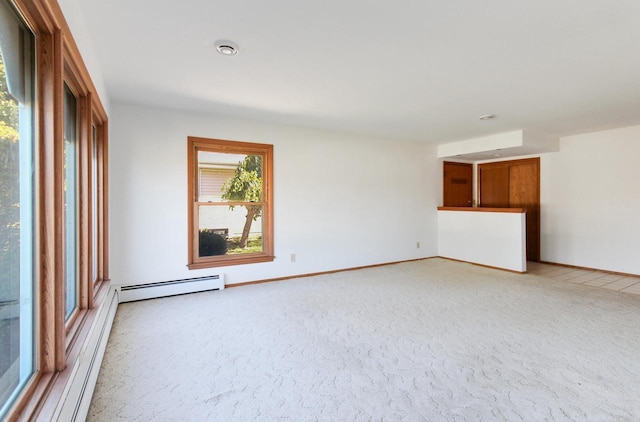 empty room featuring light colored carpet, baseboards, and a baseboard radiator