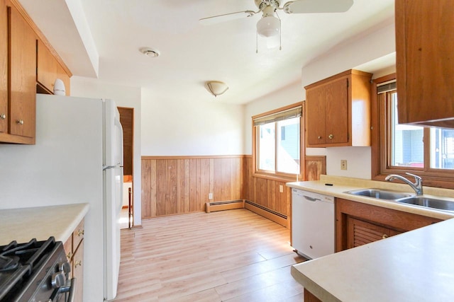 kitchen with a sink, white appliances, wainscoting, and light countertops