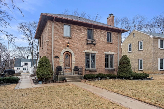 colonial-style house featuring a front lawn, brick siding, and a chimney