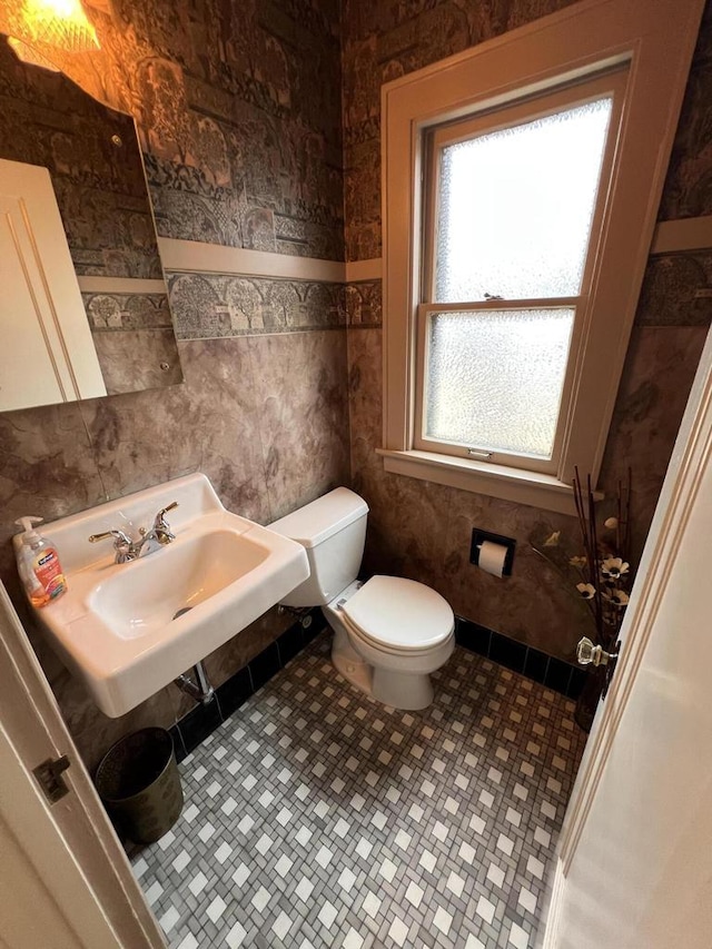 half bathroom with toilet, baseboards, and a sink