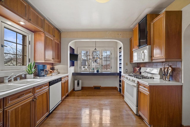 kitchen featuring a sink, white appliances, plenty of natural light, and tasteful backsplash