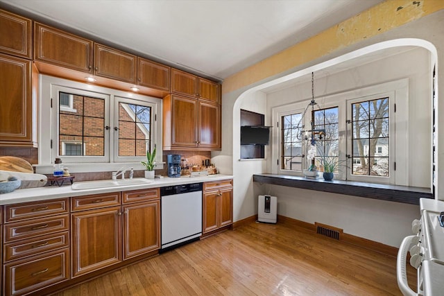 kitchen with visible vents, brown cabinets, a sink, range, and dishwasher