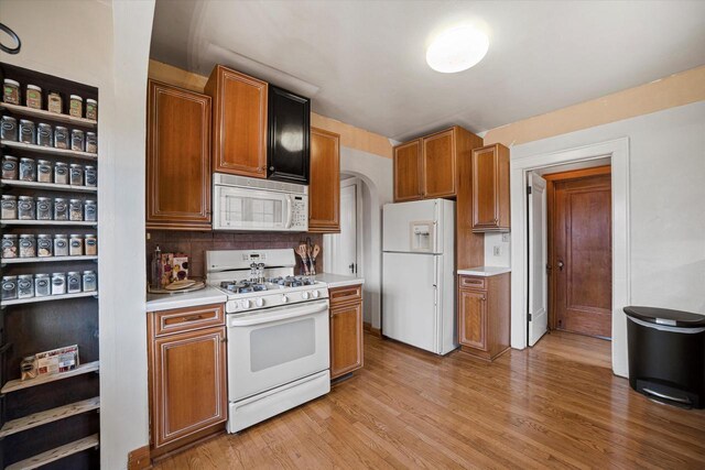 kitchen featuring white appliances, light wood-style flooring, light countertops, and backsplash