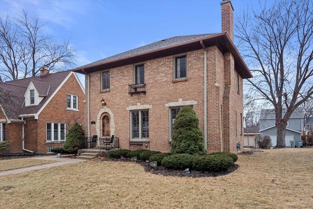 view of front of property with a front lawn, brick siding, and a chimney