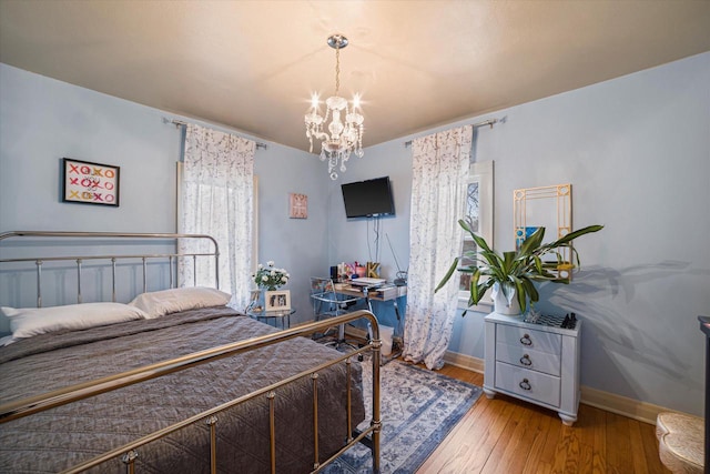 bedroom with a notable chandelier, baseboards, and hardwood / wood-style flooring