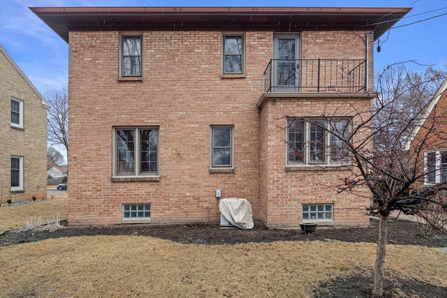 view of property exterior with a balcony, brick siding, and a lawn