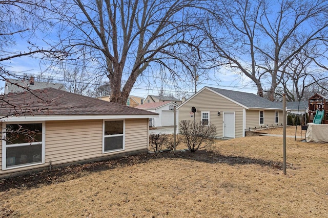 view of side of property with an outdoor structure, a playground, and a shingled roof