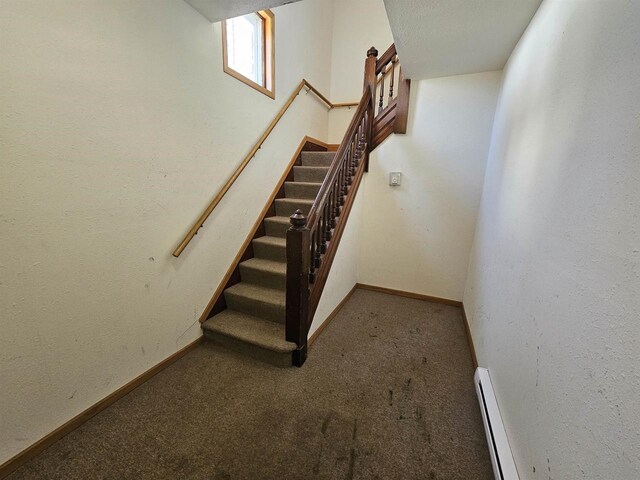 stairway featuring baseboards, baseboard heating, and carpet