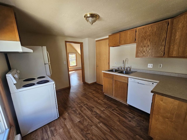 kitchen featuring brown cabinets, a sink, under cabinet range hood, dark wood-type flooring, and white appliances